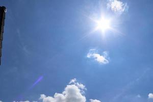 schöne aussicht auf sonnenstrahlen mit einigen linseneffekten und wolken am blauen himmel foto