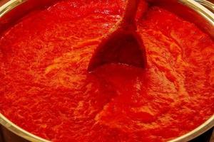 eine frau bereitet frischen gesunden saft aus tomaten zu. Frisch zubereiteter Tomatensaft wird in einem Topf gekocht und für die Langzeitlagerung konserviert. diätkonzept für einen gesunden lebensstil. foto