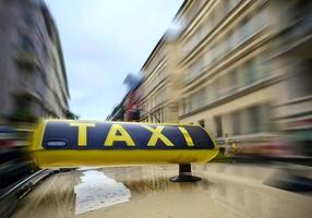 Ein Taxischild auf einem Auto mit viel Bewegungsunschärfe auf dem Hintergrund der Stadt aufgrund hoher Geschwindigkeit. foto