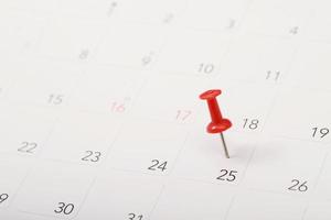 Markieren Sie den Veranstaltungstag mit einer roten Stecknadel. Reißnägel im Kalenderkonzept für die Zeitleiste, Aktivitätsplan organisieren, Terminerinnerung. planung von geschäftstreffen oder reiseplanungskonzept. foto