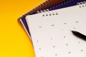 Nahaufnahme des Kalenderplans von oben, um jeden Tag einen Termin zu vereinbaren oder den Zeitplan zu verwalten, lag auf gelbem Hintergrund für die Planung von Arbeits- und Reisekonzepten. foto