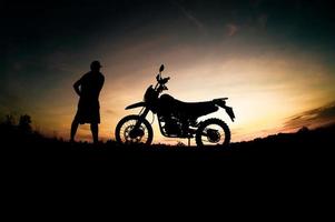 Herren-Silhouetten und Touren-Motocross-Bikes. Park zum Entspannen in den Bergen am Abend. abenteuerreise- und freizeitkonzept foto