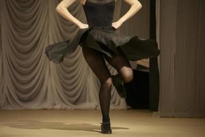 Das Mädchen tanzt in einem schwarzen Kleid. eine Frau zeigt eine Tanzbewegung. foto
