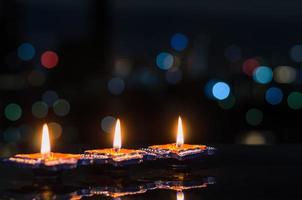 Selektiver Fokus auf die Flamme der ersten Ton-Diya-Lampen, die auf dunklem Hintergrund mit bunten Bokeh-Lichtern beleuchtet werden. diwali-festkonzept. foto