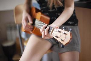 Das Mädchen spielt auf der Ukulele. Unterricht Gitarre spielen. foto