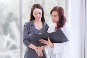 junge asiatische geschäftsfrau steht und spricht mit dem manager, um sich intensiv über die arbeit im büro zu beraten. foto