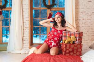 schöne Frau im Schlafanzug mit Geschenkbox, Fenster im Hintergrund. foto