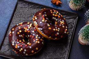 Gebäck-Konzept. Donuts mit Schokoladenglasur mit Streuseln, auf einem dunklen Betontisch foto