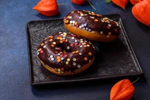 Gebäck-Konzept. Donuts mit Schokoladenglasur mit Streuseln, auf einem dunklen Betontisch foto
