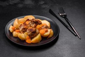 Rindfleisch und Gemüseeintopf auf einem schwarzen Teller mit Bratkartoffeln foto
