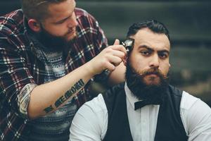 Friseur rasiert einen bärtigen Mann foto