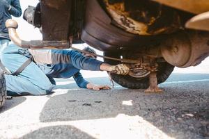 Mann liegt unter einem 4x4-Auto auf einer unbefestigten Straße foto