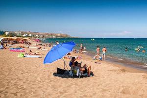 Menschen entspannen am Sandstrand im Resort Faliraki auf der Insel Rhodos, Griechenland foto
