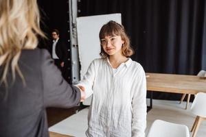 Zwei Geschäftsfrauen geben sich im Büro die Hand foto