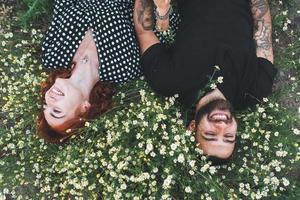 junges Paar liegt mit Gänseblümchen auf dem Feld. foto