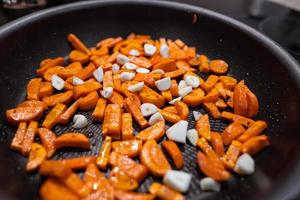 Karotten, Knoblauch in einer Pfanne vor dem Kochen. blick schließen foto
