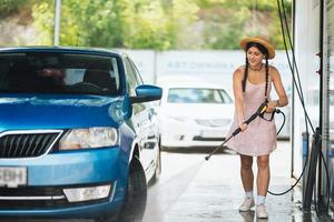 Brünette aus einem Hochdruckschlauch wäscht das Auto foto