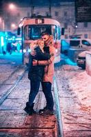 junges erwachsenes Paar auf der verschneiten Straßenbahnlinie foto