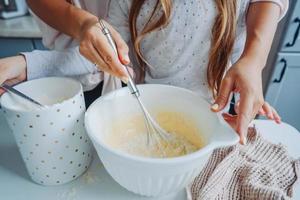 mama bringt ihrer kleinen tochter bei, essen zu kochen foto