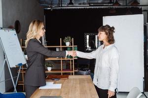 Zwei Geschäftsfrauen geben sich im Büro die Hand foto