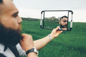 bärtiger Mann, der sich auf dem Feld rasiert foto