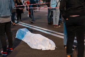 menschlicher Körper, bedeckt von einem Laken, das auf der Straße liegt. foto