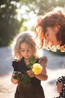 Mutter und kleine Tochter mit einer gelben Rose foto