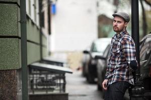 der Mann in den authentischen Stiefeln und Webkantenjeans vor dem Hintergrund der Altstadt foto