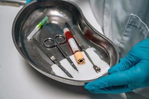 Krankenschwester in Gummihandschuhen, die ein Tablett mit chirurgischen medizinischen Geräten hält foto