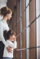 Zwei Mädchen unterschiedlichen Alters starren in ein Fenster in der Turnhalle foto