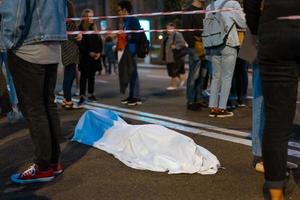 menschlicher Körper, bedeckt von einem Laken, das auf der Straße liegt. foto