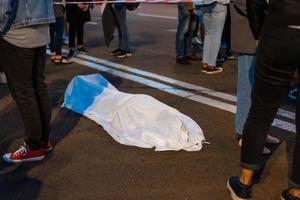 menschlicher Körper, bedeckt von einem Laken, das auf der Straße liegt. foto