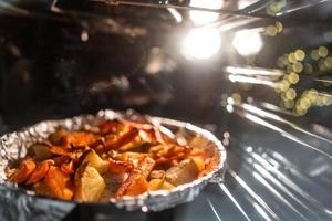 Bratkartoffeln mit Karotten und anderen Gewürzen im Bräter. foto