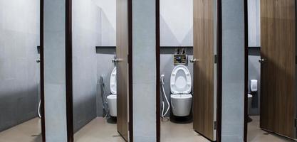 moderne öffentliche toilette mit weißer toilettenschüssel aus keramik mit grauer wand foto