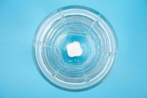 pille löst sich in einem glas wasser auf einer blauen hintergrunddraufsicht auf foto