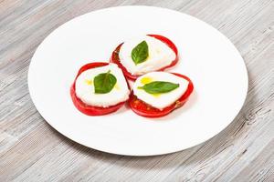 Stapel von geschnittenem Mozzarella-Käse, Tomate, Basilikum foto