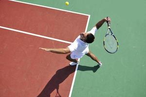 junger Mann spielt Tennis im Freien foto