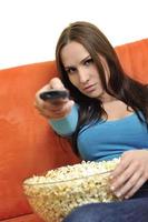 junge frau isst popcorn und sieht fern foto