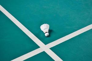 Cremeweißer Badmintonfederball auf grünem Boden im Indoor-Badmintonplatz, verschwommener Badmintonhintergrund, Kopierraum foto