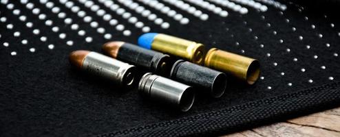 9-mm-Pistolenkugeln und Kugelschalen auf schwarzem Lederhintergrund, weicher und selektiver Fokus foto