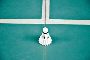 Cremeweißer Badmintonfederball auf grünem Boden im Indoor-Badmintonplatz, verschwommener Badmintonhintergrund, Kopierraum foto