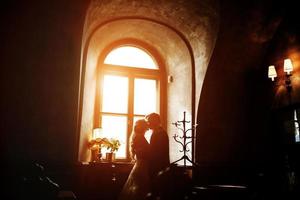 Braut und Bräutigam in einem gemütlichen Haus, fotografiert mit natürlichem Licht aus dem Fenster. foto