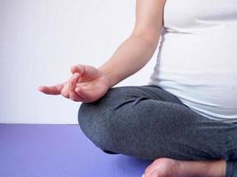 schwangere frau, die zu hause yoga macht foto