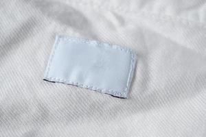 Weißes, leeres Wäschepflegeetikett auf Baumwollhemd foto