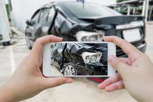 autounfall mit der hand beschädigt, indem das smartphone fotografiert wird foto