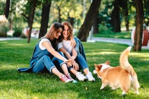 zwei Freundinnen im Park spielen mit kleinem Hund foto
