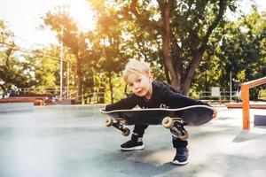 kleiner Junge, der versucht, ein Skateboard aufzuheben foto