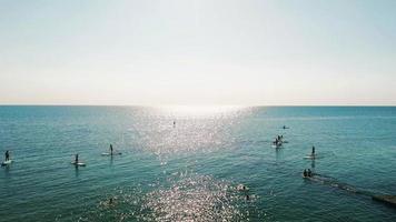 touristen, die auf sup-bord im blauen meer schwimmen. Clip. foto