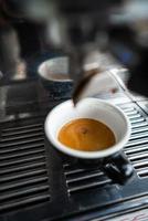 kleine Tasse Espresso, die in der stählernen Kaffeemaschine steht foto