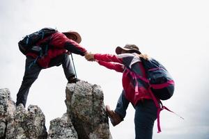 Person Wanderung Freunde helfen sich gegenseitig auf einen Berg. mann und frau geben eine helfende hand und einen aktiven fitten lebensstil. asien paar wandern helfen sich gegenseitig. konzept der freundschaft, teamarbeit. foto